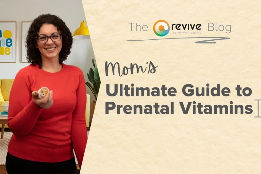 A smiling woman with curly dark hair, wearing glasses and a red sweater, holds out a small container of prenatal vitamins in a cozy living room with colorful pillows and framed artwork on the wall. On the right side, a beige background displays the text 'Mom’s Ultimate Guide to Prenatal Vitamins' with 'The Revive Blog' logo above it.