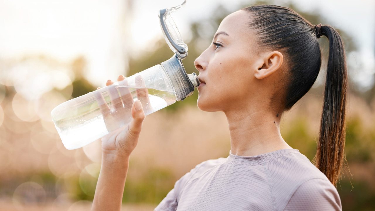 Fitness, health and woman drinking water in nature after exercise, training or workout. Sports, nut.